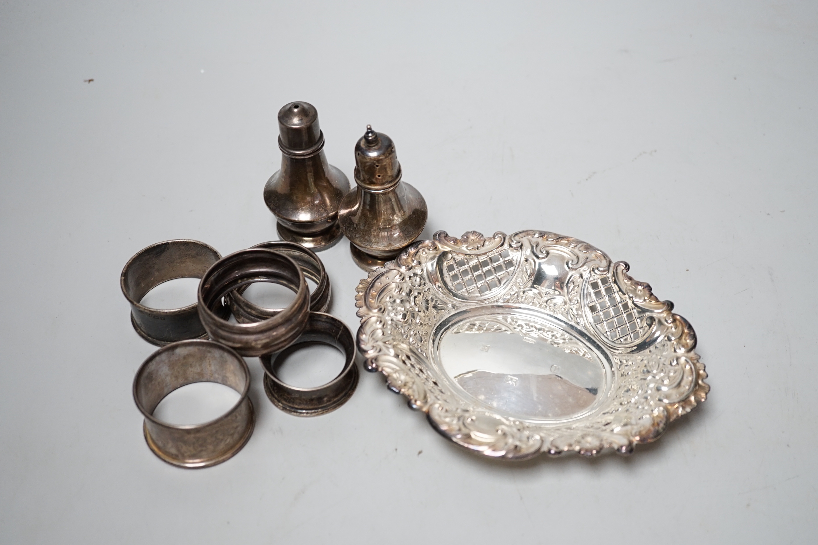 A modern silver bon bon dish, 15.4cm, five silver napkin rings and a pair of silver pepperettes.